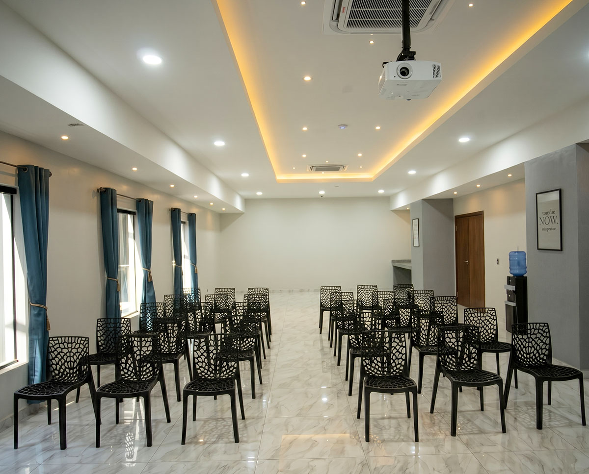 Salão de eventos do Los Olivos Hotel com cadeiras, projetor e tela